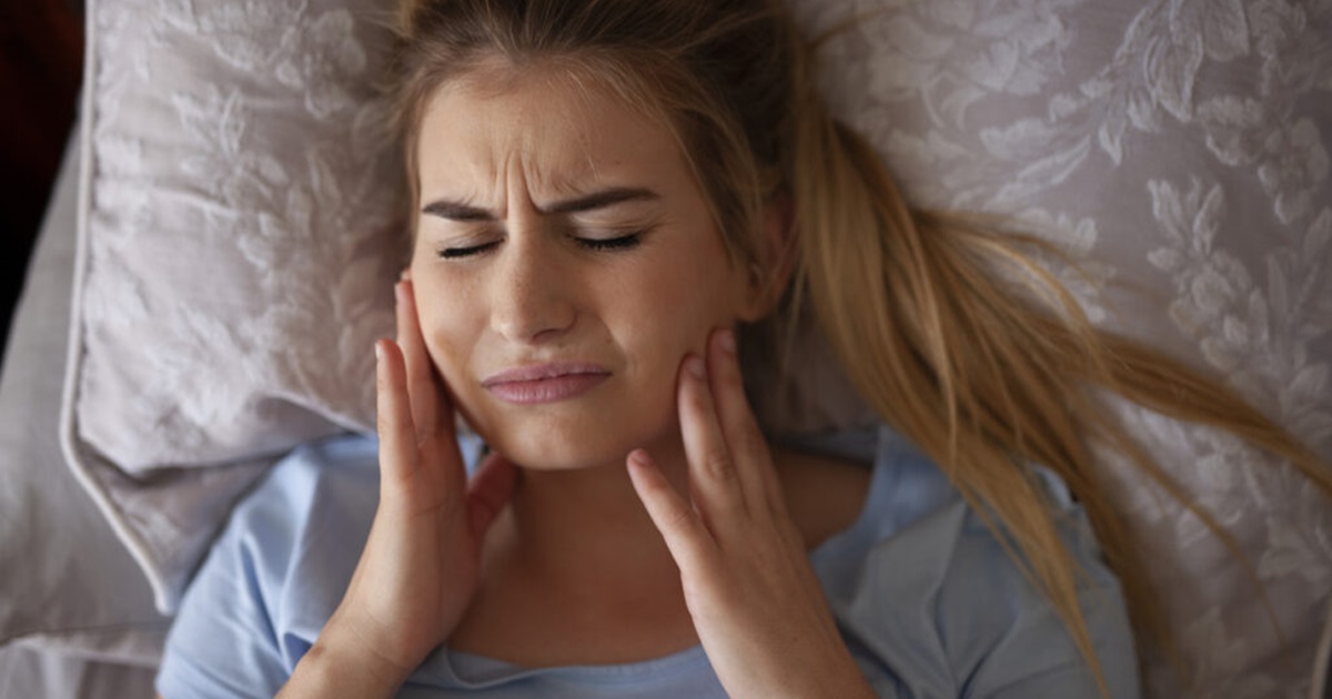 Woman at home holding her jaw during a weekend dental emergency North York