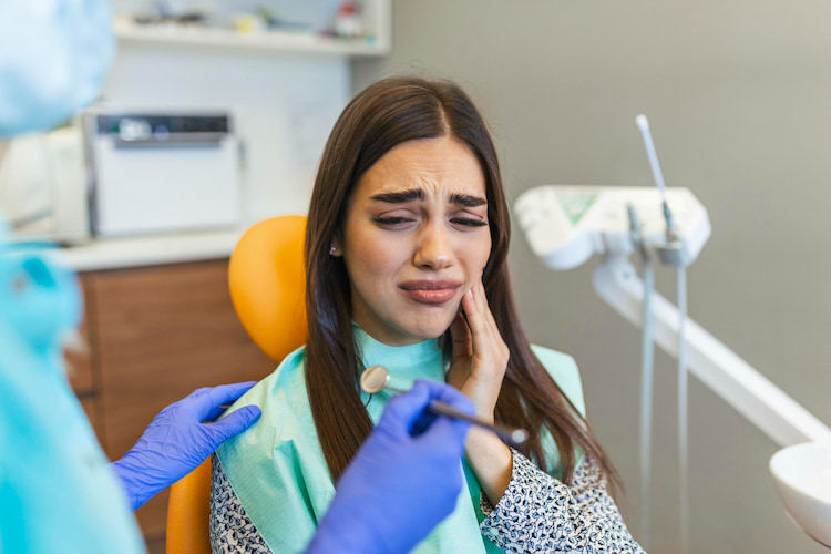 a patient sitting at a dental chair, as she's dealing with tooth extraction infection signs.